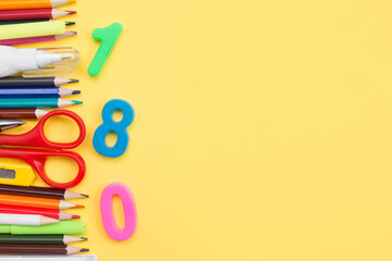 Back to school background, stationery for kids and colorful numbers on yellow with a copy space
