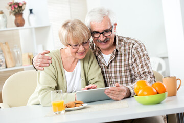 Elderly couple have fun at home with a tablet computer