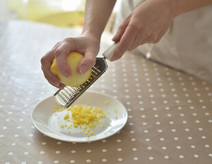 Closeup of woman rubbing lemon zest on grater