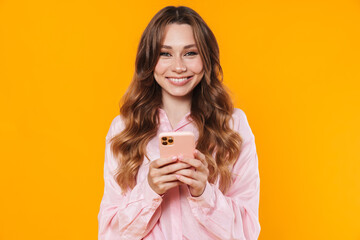 Image of beautiful pleased woman smiling and using mobile phone