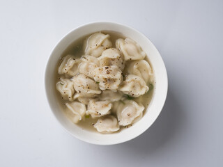 Russian dumplings in the broth. White round bowl on a white background