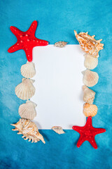 Fototapeta na wymiar Seashell and starfish with the blank paper page on a blue background