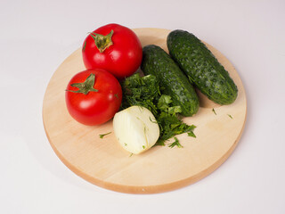 Tomatoes, cucumbers, onions and herbs on the board. Cooking for a salad. Vegetable ingredients