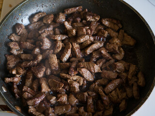 The meat is fried in a pan. Beef stroganoff cooking. Close-up
