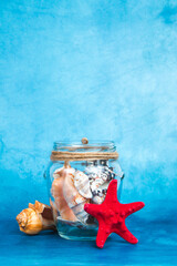 Jar full of seashells with the starfish on a blue background