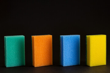 different color washes for washing dishes on a textured black background.  copy space.