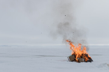 Fire and smoke from burning trash on a snow covered field
