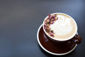 Cup of coffee on black rustic background with beautiful latte. Coffee foam with flowers. Cappuccino. 