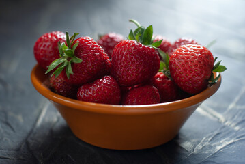 strawberries in a ceramic bowl on a concrete table,