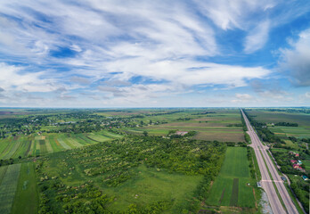 Summer rural landscape, aerial view. View of green fields, forest, village and highway