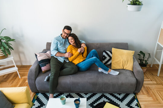 Cheerful romantic couple is sitting on sofa together stock photo