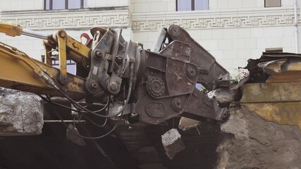 Hydraulic power claw destroying a building’s wall
