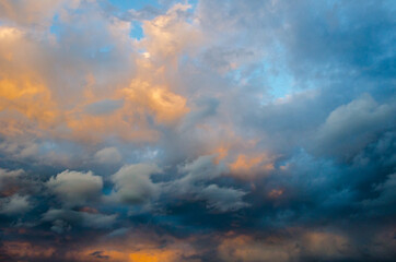 Abstract pattern of white light clouds, illuminated by the sun, against a blue sky.