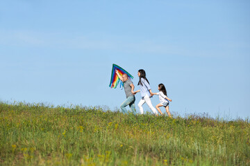 happy family with child girl launches kite against the blue sky in sunny summer day. Carefree time