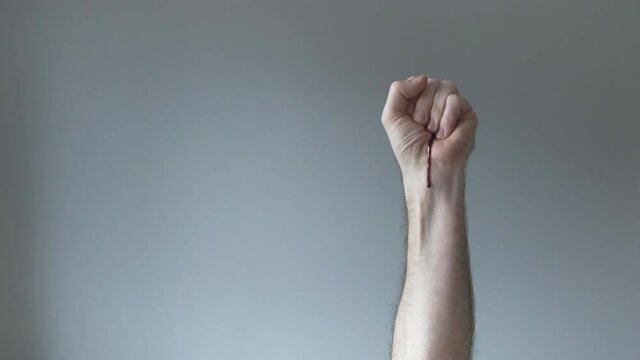 Bleeding clenched fist with copy space over gray background