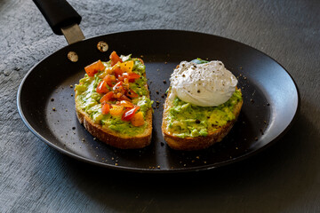 Tasty sandwich with poached egg, avocado and tomatoes