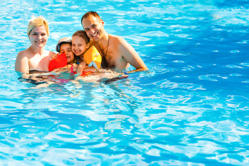 Young family, parents with children, in pool