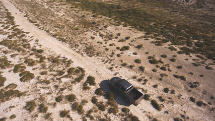 Aerial photo from flying drone of a riding pickup car in Texas desert with arid climate and dry landscape. Tourists having leisure time with rental automobile during their road trip to America