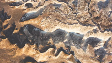Top view aerial photo from drone of brown arid wilderness landscape with range shadows at sunset. View from the high with evening light slowly reaches into the valleys of boundless desert in Kazahstan