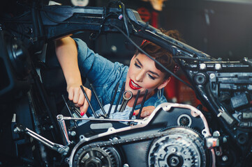 Fototapeta na wymiar beautiful girl repairs a motorcycle in a workshop, pin-up style, service and sale
