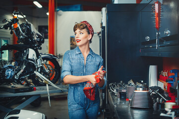 beautiful girl repairs a motorcycle in a workshop, pin-up style, service and sale