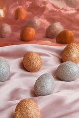 Golden and silver Easter eggs on a pink and coral background