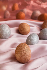 Golden and silver Easter eggs on a pink and coral background