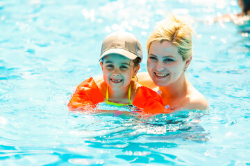 Mother and the daughter at pool, summer holidays