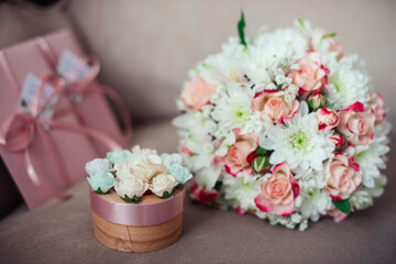 Close-up of a Wedding bouquet of pink roses and white chrysanthemums on a background of pink certificates and a box on a powdery sofa