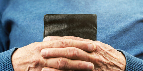 aged person in blue pullover hands hold small black wallet