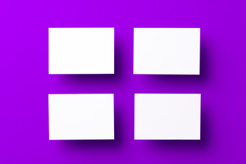 Blank white businesscards on purple background, copy space