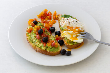 Tasty sandwich with poached egg, avocado and tomatoes