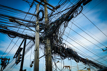 An electric pole with tangled wires in an Asian style. The chaos of electric wires in Phuket, Thailand.