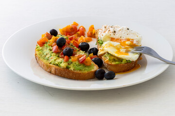 Tasty sandwich with poached egg, avocado and tomatoes