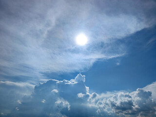 The sun against the blue sky and white clouds
