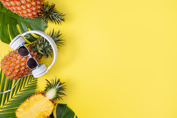 Funny pineapple wearing white headphone, listen music, isolated on yellow background with tropical...