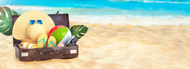 Summer vacation concept. Beach and the sea, sunny day summer banner. Flip flops, sun glasses, shells, camera, beach ball, luggage. 