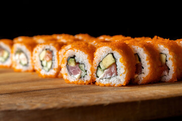 California rolls laid out on a wooden plank. Big set.