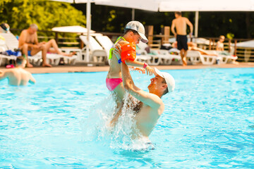 Father playing with his daughter in swimming pool