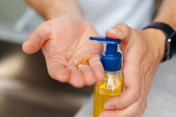 Man washing hands with soap in a sink at his home