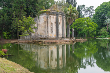 Аn abandoned building in the middle of a pond at the English Garden of Caserta Royal Palace, Italy. Ruins of a temple.