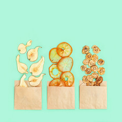 Healthy snack, set of dried fruits. Dehydrated fruit chips of banana, persimmon, pear in paper package. Diet food. Top view.