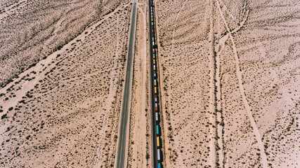 Aerial view of train containers shipping goods in wild environment, locomotive freight on railroad transporting cargo through desert lands in Arizona. Logistic and delivery shipping goods everywhere