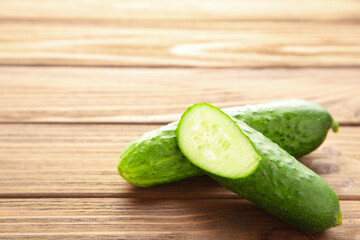 Fresh cucumber and slices on brown wooden background.