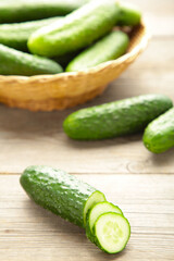 Fresh cucumbers in basket on grey background.