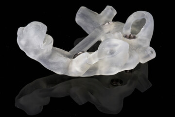 Fototapeta premium dental template resting on the patient’s teeth for implantation, shot on a black background side view