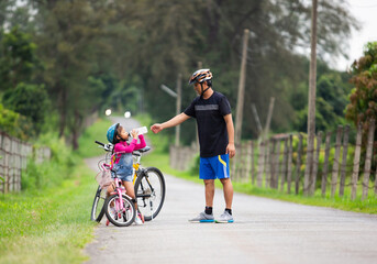 father let his daughter drink water while cycling in the park