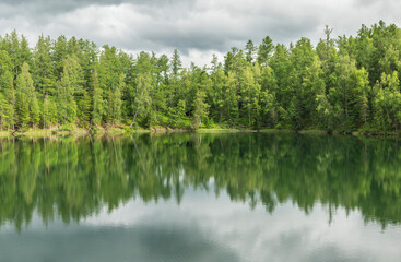 Wild forest lake. Gloomy sky, beautiful reflection. Travel and summer vacation.