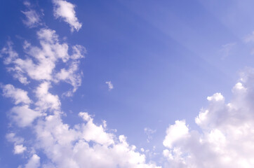 Blue sky with clouds on a sunny bright day. A ray of sun shines through the clouds. Calm and serene mood. Heaven.