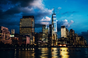 Scenery view of Lower Manhattan skyline at evening with city lights reflected in Hudson river....